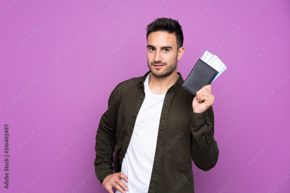 Young handsome man over isolated purple background happy in vacation with passport and plane tickets Young handsome man over isolated purple background happy in vacation with passport and plane tickets