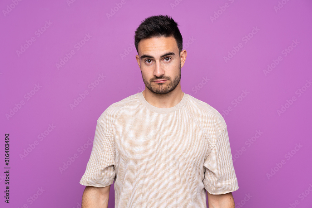 Fototapeta premium Young handsome man over isolated purple background with sad and depressed expression