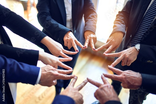 Group of business workers standing on a circle doing symbol with fingers together at the office.