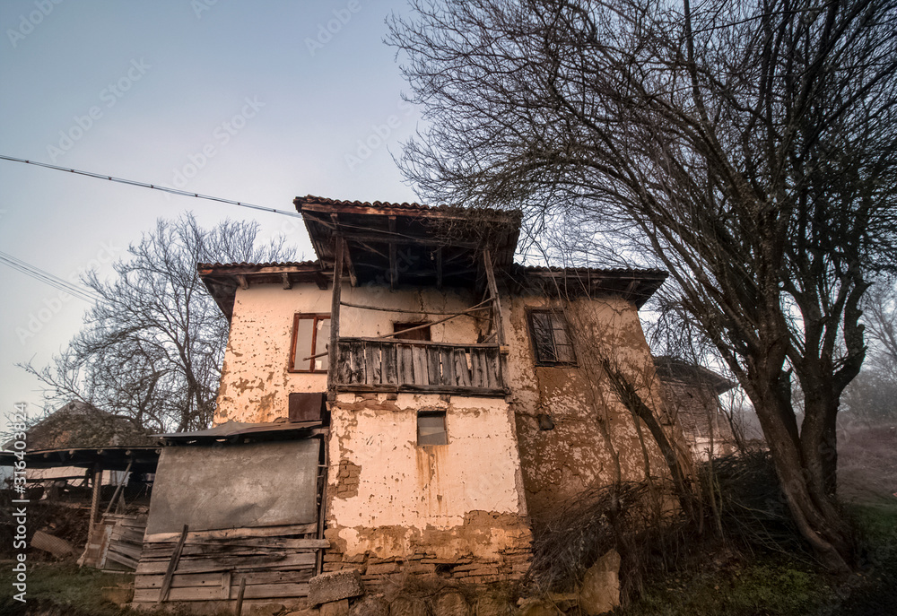 A series of misty landscapes in winter. An abandoned old house near a rural path in a mountain village Smolichano in the Osogovo Balkan. Bulgaria. A series of misty landscapes in winter. An abandoned old house near a rural path in a mountain village Smolichano in the Osogovo Balkan. Bulgaria.