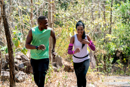 Fototapeta Naklejka Na Ścianę i Meble -  Young Black Couple Running at Forest Trail.