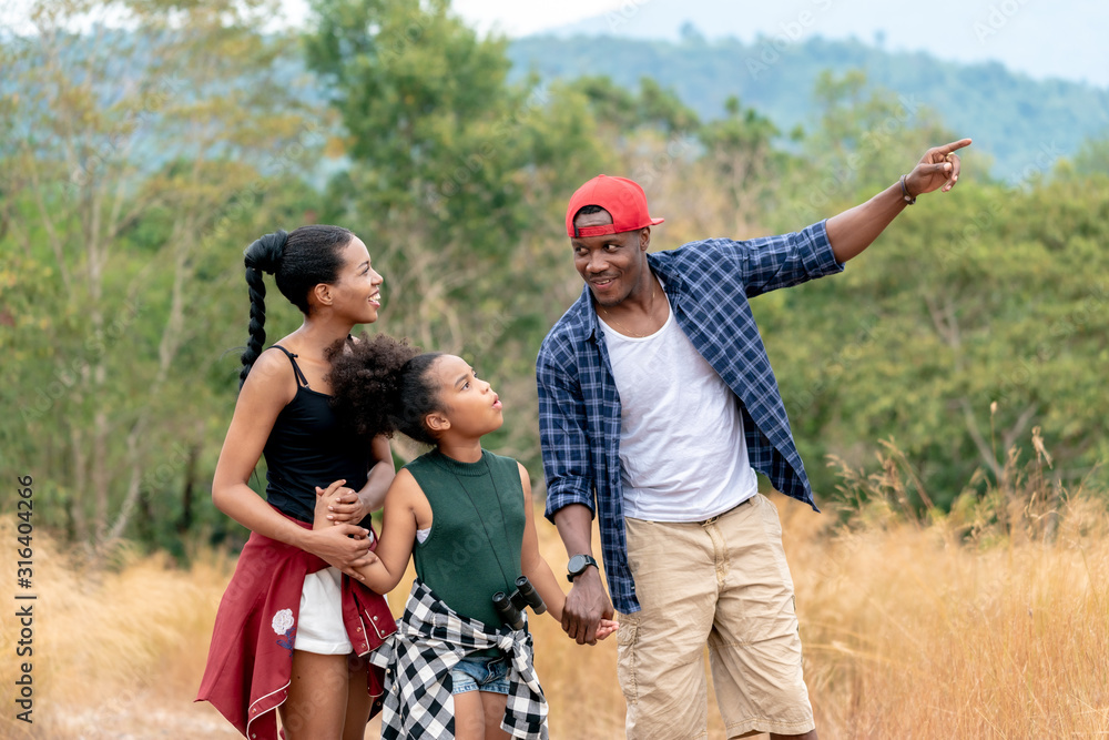 African American Family On Hiking Adventure Through Forest.