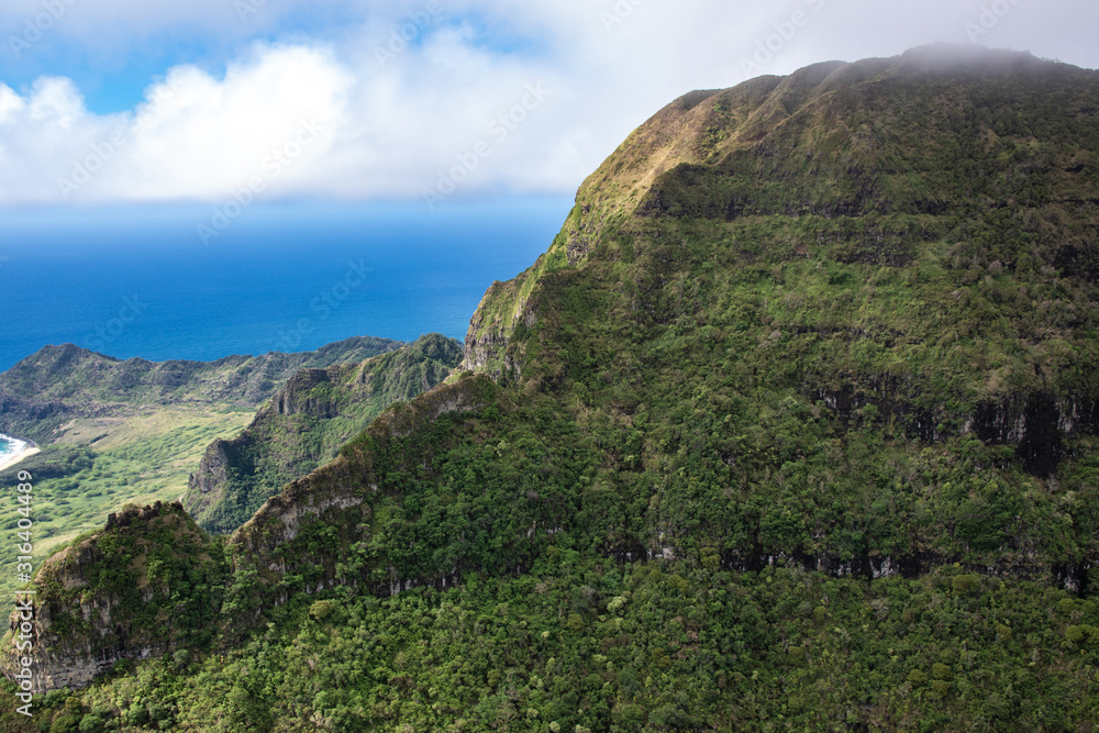 Aerial view of Kauai's lush colorful interior mountain landscape. The southern coast can be seen in the background. 