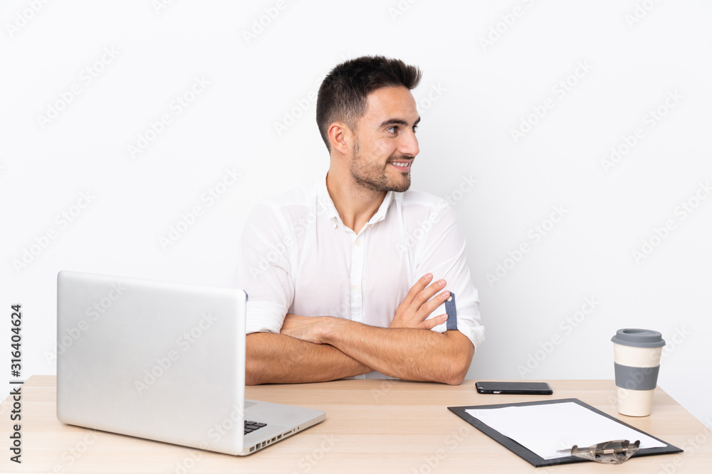 Young business man with a mobile phone in a workplace laughing Young business man with a mobile phone in a workplace laughing