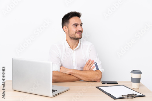Young business man with a mobile phone in a workplace looking to the side