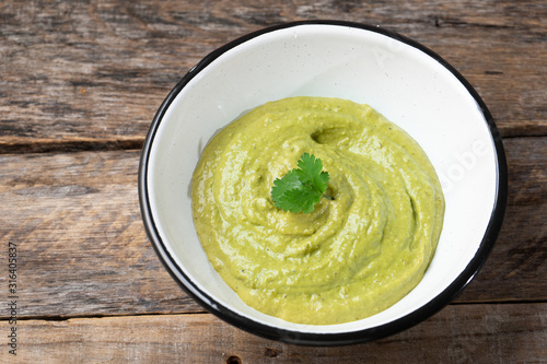 Mexican creamy green sauce with jalapeno pepper on wooden backgrond photo