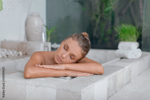 Young girl enjoys spa treatments in the bathroom with flowers.