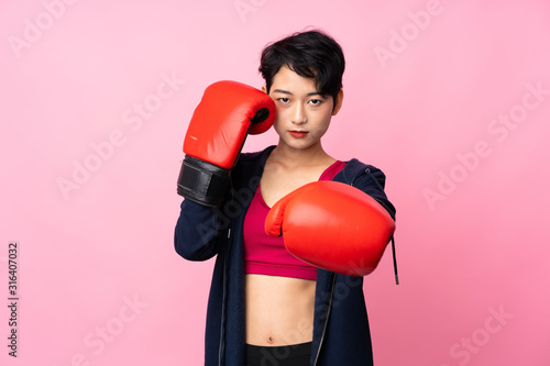 Young sport Asian woman over isolated pink background with boxing gloves