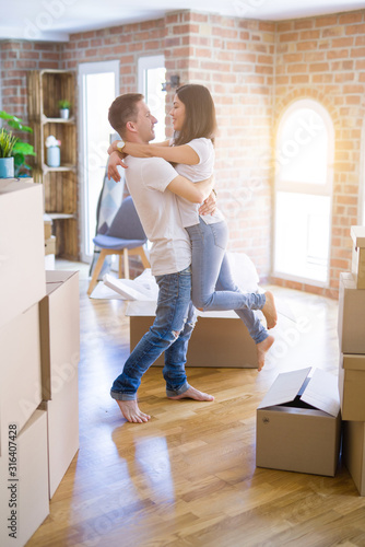 Young beautiful couple hugging at new home around cardboard boxes © Krakenimages.com