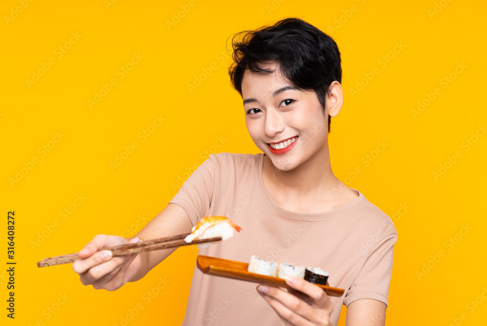 Young Asian girl with sushi over yellow background Young Asian girl with sushi over yellow background