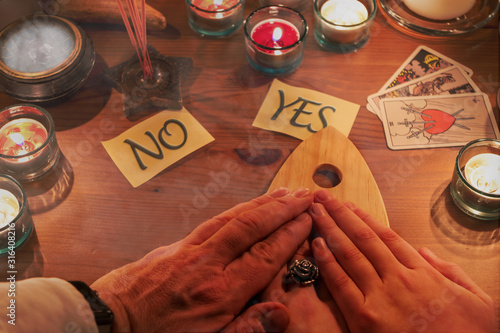 Geisterbefragung von drei Menschen mit Hilfe eine Ouija Bretts bei Kerzenschein