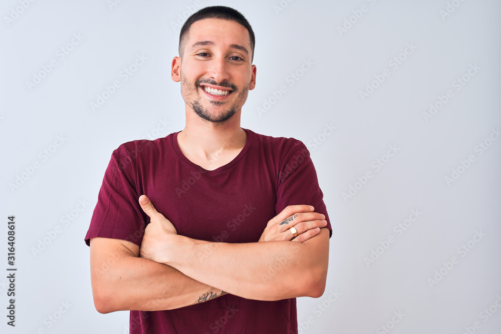 Young handsome man standing over isolated background happy face smiling with crossed arms looking at the camera. Positive person. - obrazy, fototapety, plakaty 