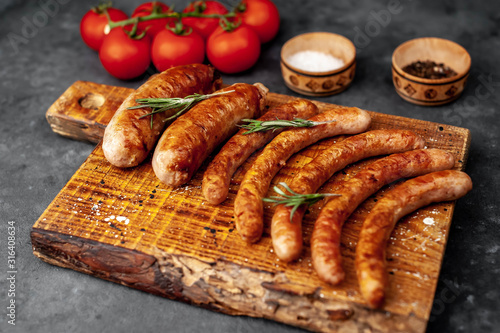 Various grilled sausages with spices on a stone table with copy space for your text.