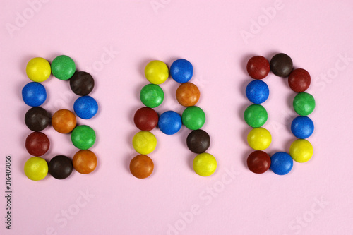 Word bad of multicolored candies on pink background © Michael