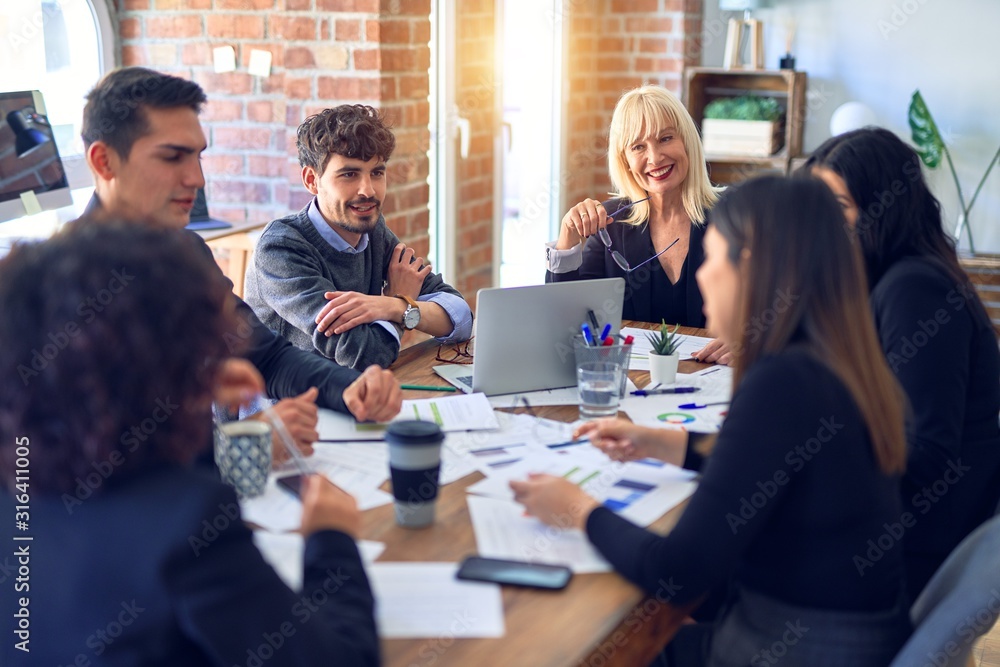 Group of business workers smiling happy and confident. Working together with smile on face using laptop and speaking at the office Group of business workers smiling happy and confident. Working together with smile on face using laptop and speaking at the office