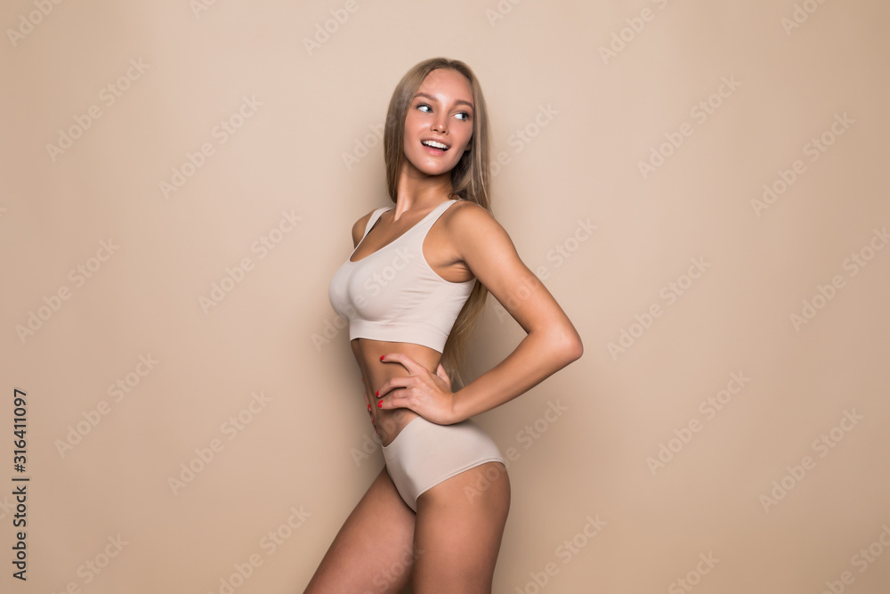 Young beautiful woman with with perfect body in nice lingerie on beige background. - obrazy, fototapety, plakaty 