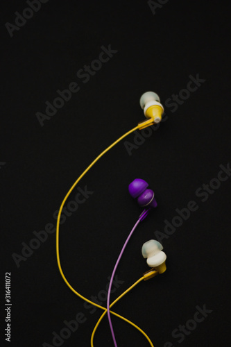  Yellow and purple headphones on black background © Тамара Печеная