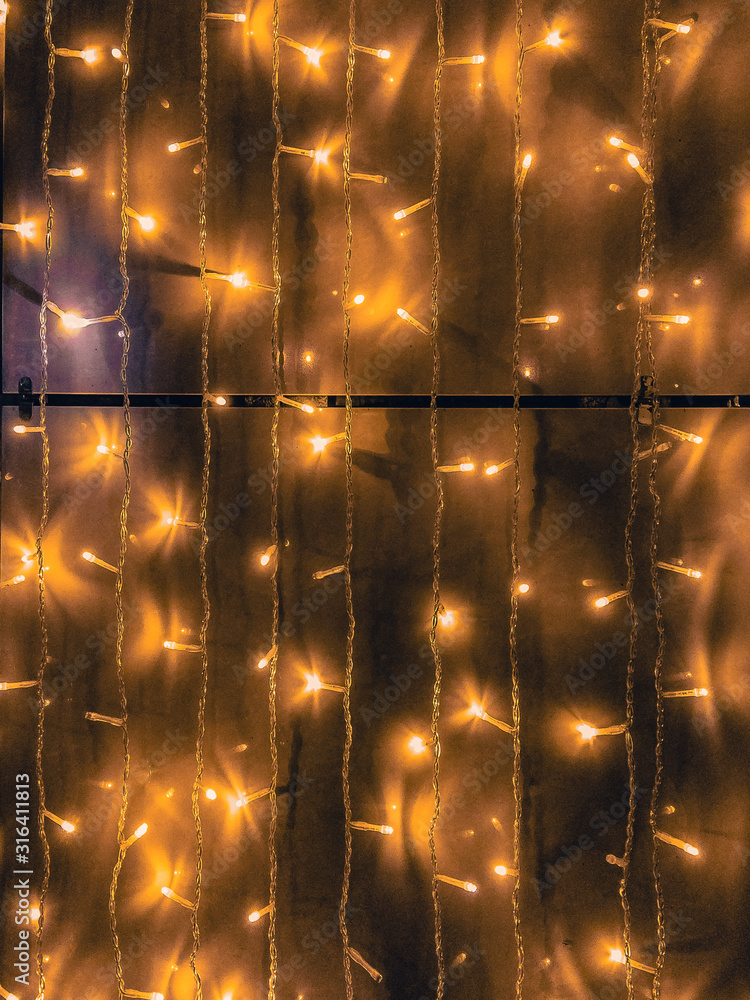 Yellow LED garland lights on a vertical surface at night. Background image.  Stock Photo | Adobe Stock
