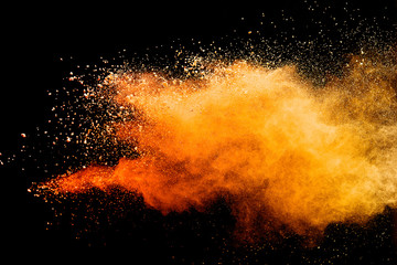 Abstract orange powder explosion isolated on black background.