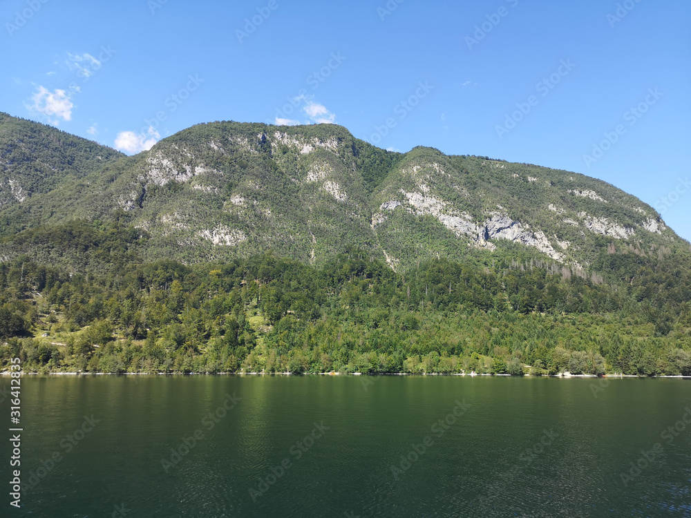 Beautiful view of the crystal clear Bohinj lake from the water with the mountains in the background Beautiful view of the crystal clear Bohinj lake from the water with the mountains in the background