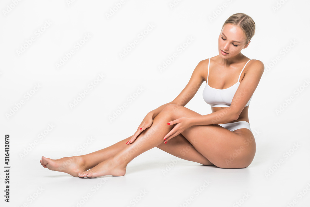 Perfect Body, Beautiful Woman. Young woman with beautiful body - legs, arms, shoulders, sitting on a floor. Health and beauty woman in white underwear touching her skin.