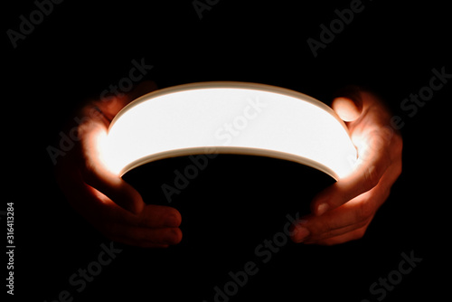 Flexible lighting oled panels in male hands on a black background photo