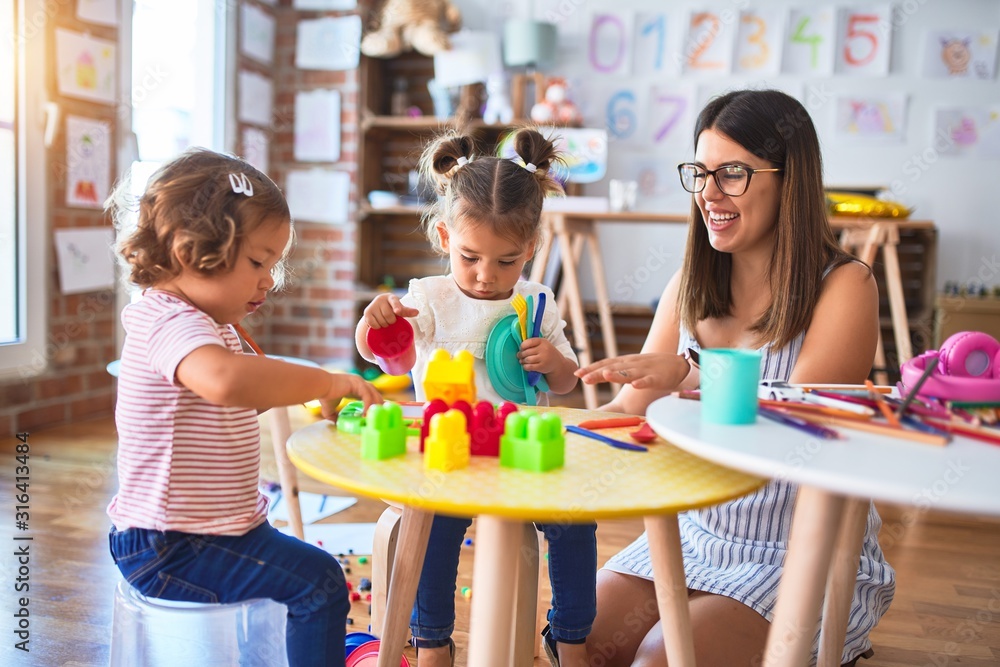 Young beautiful teacher and toddlers playing meals using plastic food and cutlery toy at kindergarten Young beautiful teacher and toddlers playing meals using plastic food and cutlery toy at kindergarten