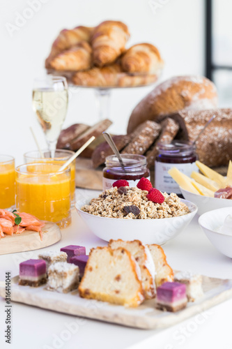 Luxurious gourmet breakfast table, presented with granola, champagne, croissants, juice, cake, bread and more