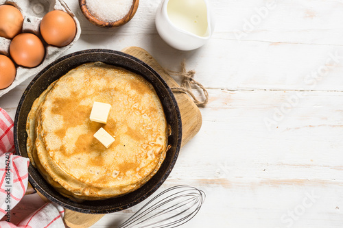 Crepes or thin pancakes in the frying pan with ingredients for cooking.