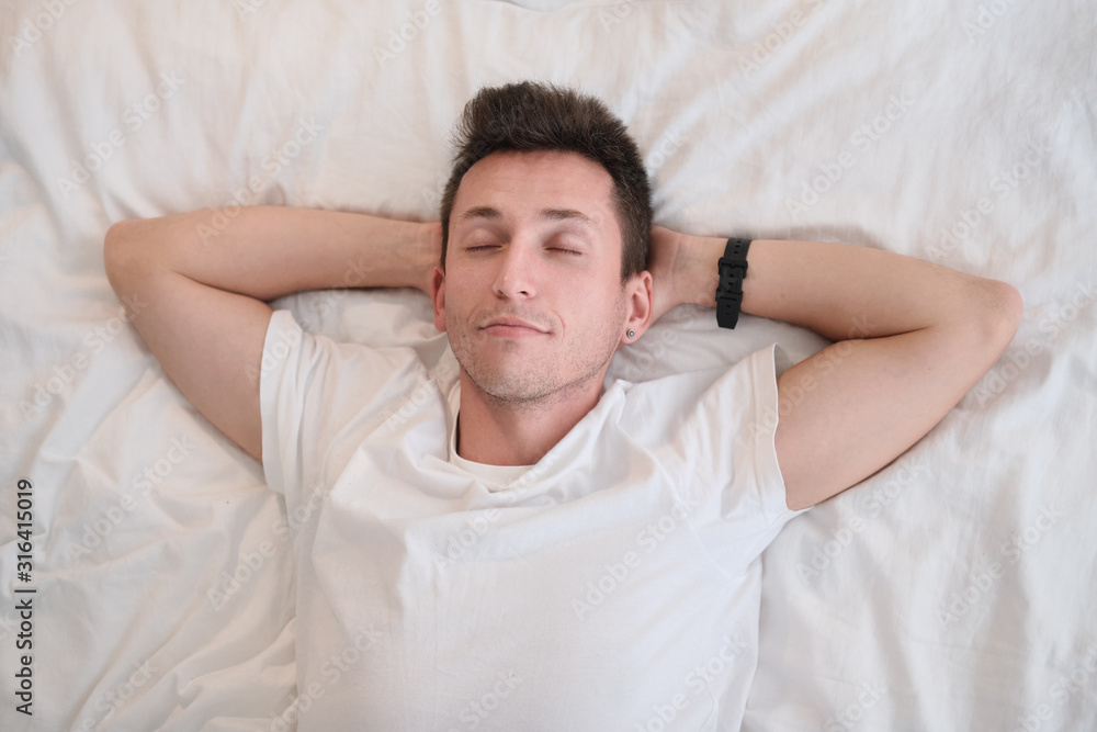 Young man in the white shirt lying on a bed with white linen. Young man in the white shirt lying on a bed with white linen.