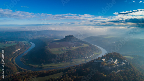 Konigstein Fortress - a Saxon mountain fortress near the town of Konigstein, located on a plateau rising 247 meters above the Elbe level, bathed in fog, aerial view