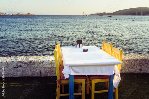 Tables in Bodrum town near beautiful Aegean Sea. Beach cafe near sea, Turkey. Sunset.