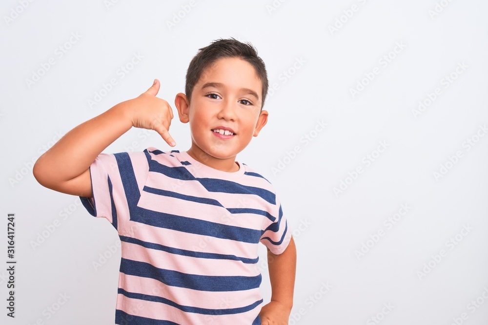 Beautiful kid boy wearing casual striped t-shirt standing over isolated white background smiling doing phone gesture with hand and fingers like talking on the telephone. Communicating concepts. Beautiful kid boy wearing casual striped t-shirt standing over isolated white background smiling doing phone gesture with hand and fingers like talking on the telephone. Communicating concepts.