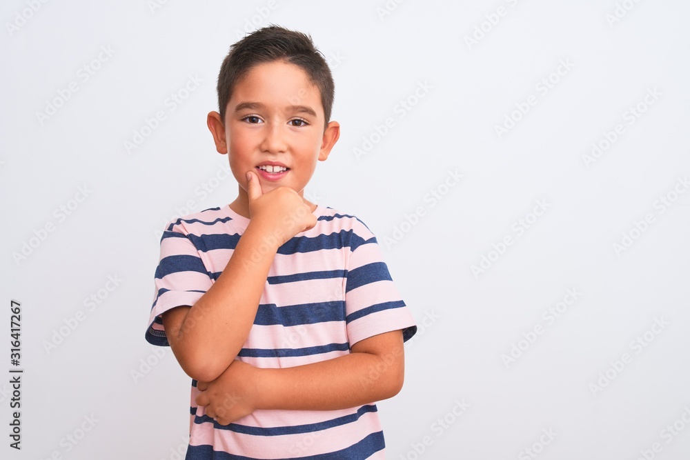 Beautiful kid boy wearing casual striped t-shirt standing over isolated white background looking confident at the camera smiling with crossed arms and hand raised on chin. Thinking positive. Beautiful kid boy wearing casual striped t-shirt standing over isolated white background looking confident at the camera smiling with crossed arms and hand raised on chin. Thinking positive.
