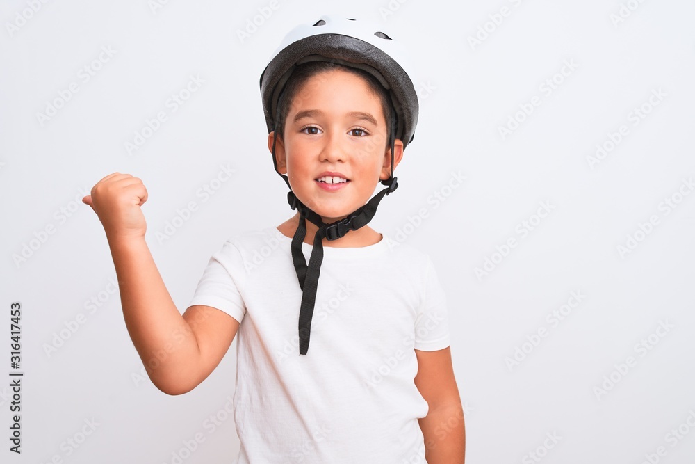 Beautiful kid boy wearing bike security helmet standing over isolated white background smiling with happy face looking and pointing to the side with thumb up. Beautiful kid boy wearing bike security helmet standing over isolated white background smiling with happy face looking and pointing to the side with thumb up.