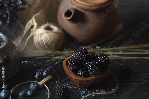 Fototapeta Naklejka Na Ścianę i Meble -  blueberries and blackberries in a vintage jar and wooden plate, lavender and dried flowers. vintage village style