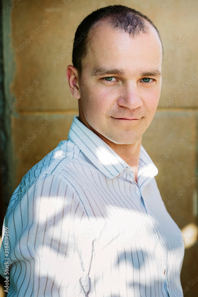 man portrait  in strip shirt friendly looks at the camera, against the background of the old wall