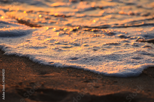 Wave with foam in a beach at the sunset