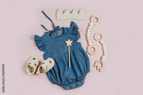 Cute set of baby clothes and accessories for girl on pink background. Blue romper with cotton crown and baby shoes. Fashion newborn bodysuit. Flat lay, top view photo