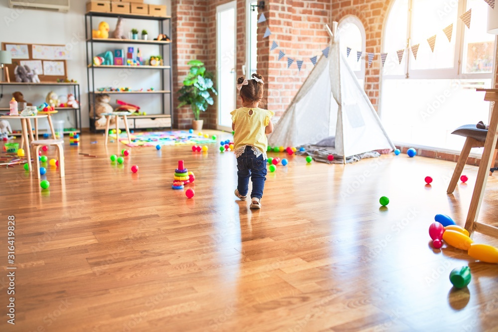 Obraz premium Beautiful toddler playing with striped straws standing at kindergarten