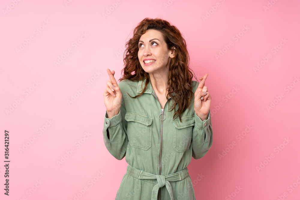 Young pretty woman over isolated pink background with fingers crossing and wishing the best Young pretty woman over isolated pink background with fingers crossing and wishing the best