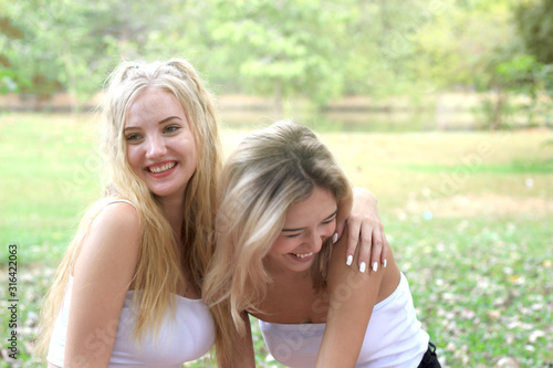 Happy friends on picnic in park, two young beautiful teen girls having fun and laughing while spending time together in the garden, woman outdoor friendship concept.