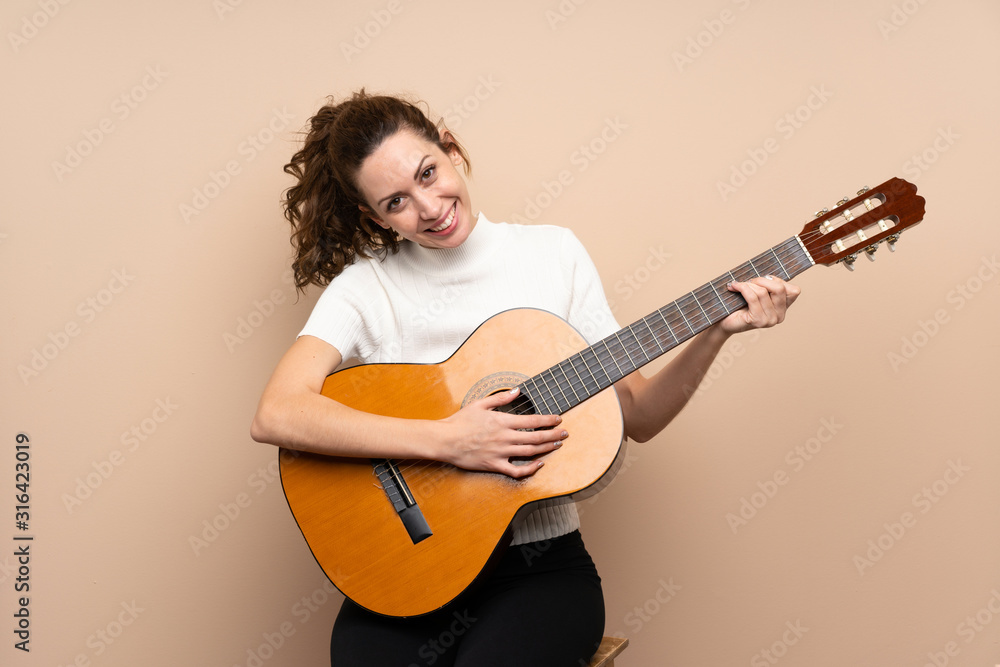 Fototapeta premium Young woman with guitar over isolated background
