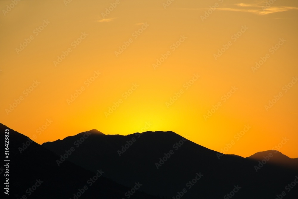 Sunset over the mountains. Golden hour. A silhouette of mountains and a golden sky lit by the last rays of the sun.