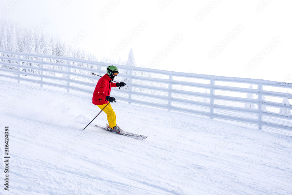 Skier in motion, skiing in mountain ski resort with beautiful winter landscape in the background