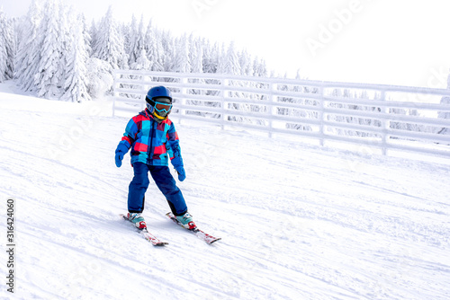 Young skier in motion, skiing in mountain ski resort with beautiful winter landscape in the background