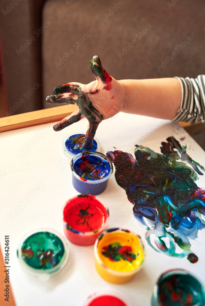 Obraz premium Hands of a child who paints with bright finger paints