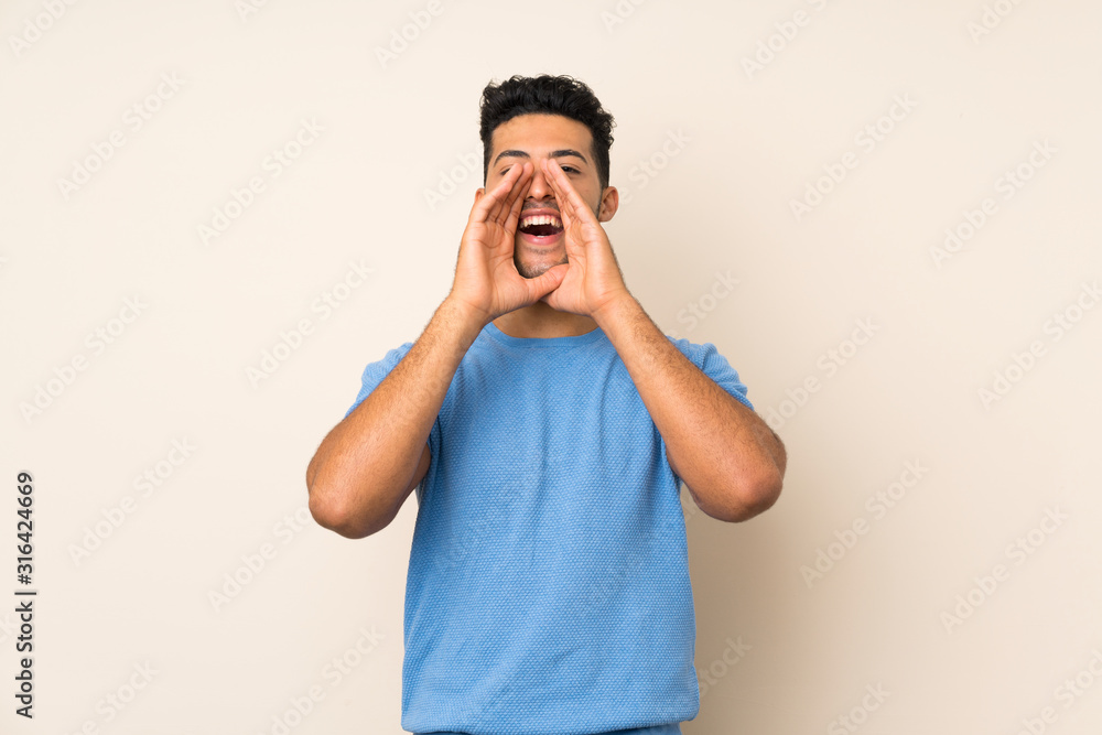Young handsome man over isolated background shouting and announcing something Young handsome man over isolated background shouting and announcing something