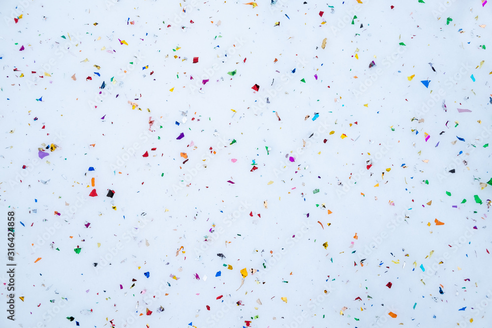 confetti scattered in the snow. Festive background. Abstract composition