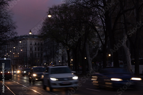 Night street with fast moving cars and a tram at a stop, Vienna, Austria